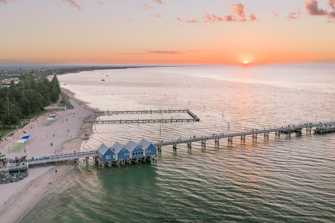 Busselton Jetty and the blue boat sheds with the sun setting behind
