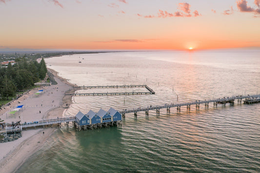 Busselton Jetty and the blue boat sheds with the sun setting behind
