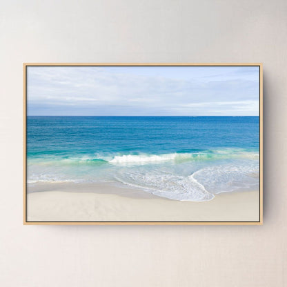 Oak framed canvas print of aerial photography of Alkimos Beach, a small wave rolling onto pale sand beneath a blue sea and cloudy sky