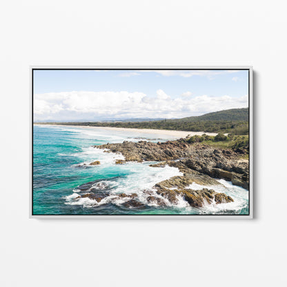 Aerial photograph of surf breaking over the headland rocks at Hastings Point NSW in a white frame