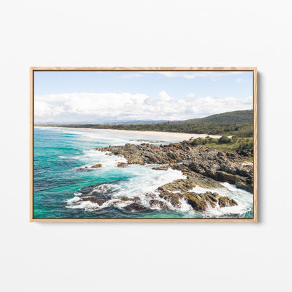 Aerial photograph of surf breaking over the headland rocks at Hastings Point NSW in an oak frame
