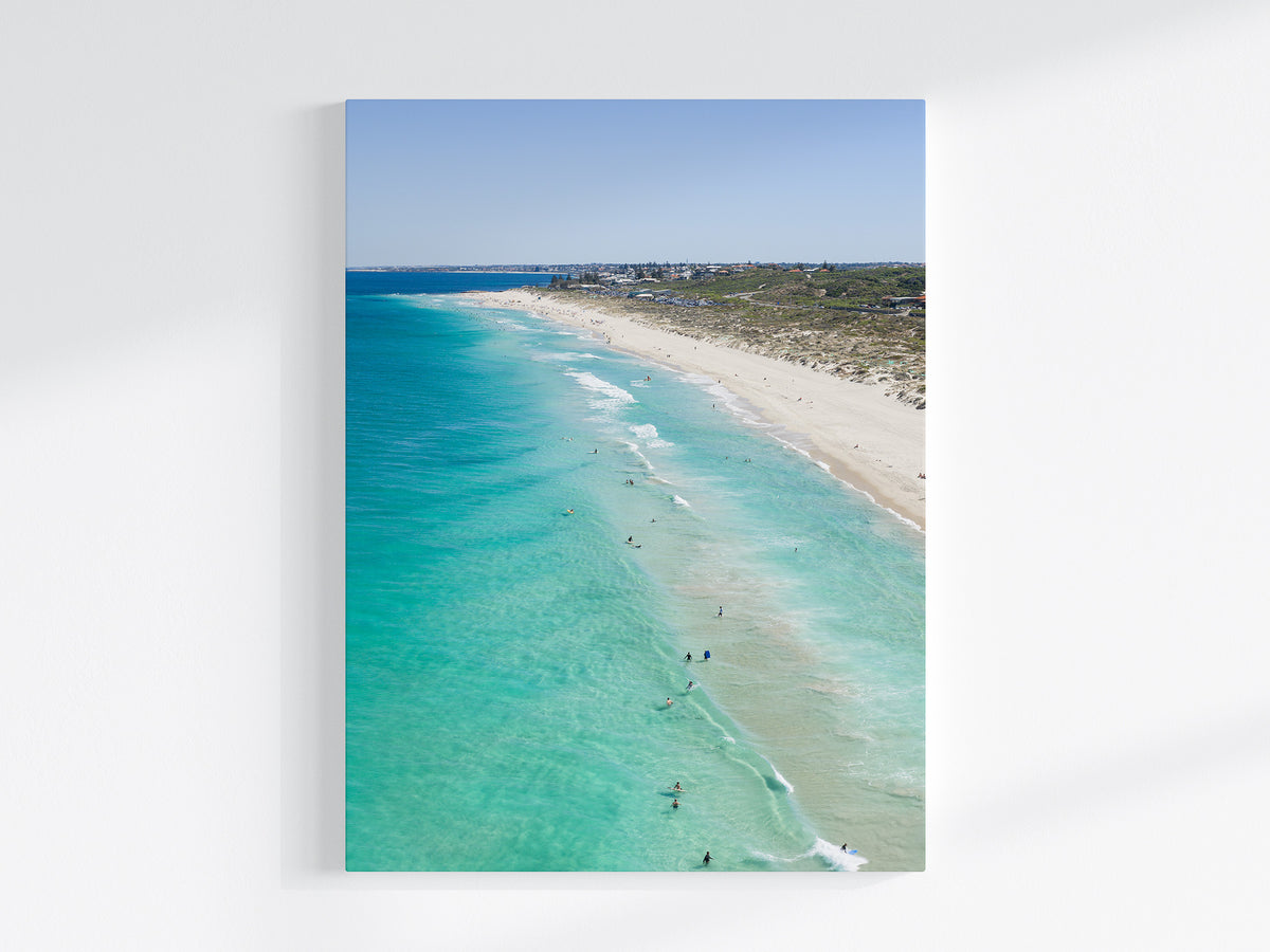 Stretched canvas print of aerial photography of Trigg Beach, a long curving beach with turquoise water, white sand and coastal bush in portrait orientation on a wall