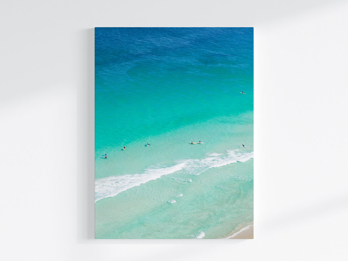 Stretched canvas print of aerial photography of Scarborough Beach, surfers and swimmers in deep turquoise water along a diagonal shoreline in portrait orientation on a wall