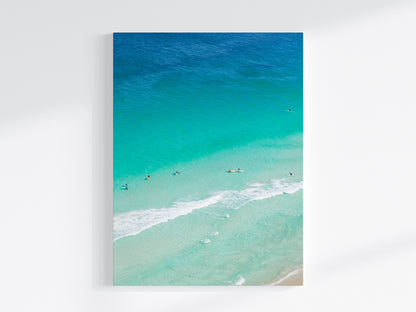 Stretched canvas print of aerial photography of Scarborough Beach, surfers and swimmers in deep turquoise water along a diagonal shoreline in portrait orientation on a wall