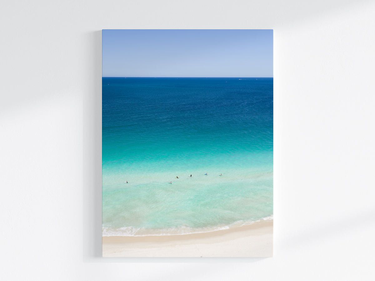 Stretched canvas print of aerial photography of Scarborough Beach, deep blue ocean meeting turquoise shallows and a white sand beach with small figures in portrait orientation on a wall