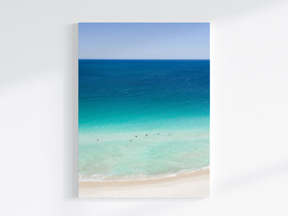 Stretched canvas print of aerial photography of Scarborough Beach, deep blue ocean meeting turquoise shallows and a white sand beach with small figures in portrait orientation on a wall