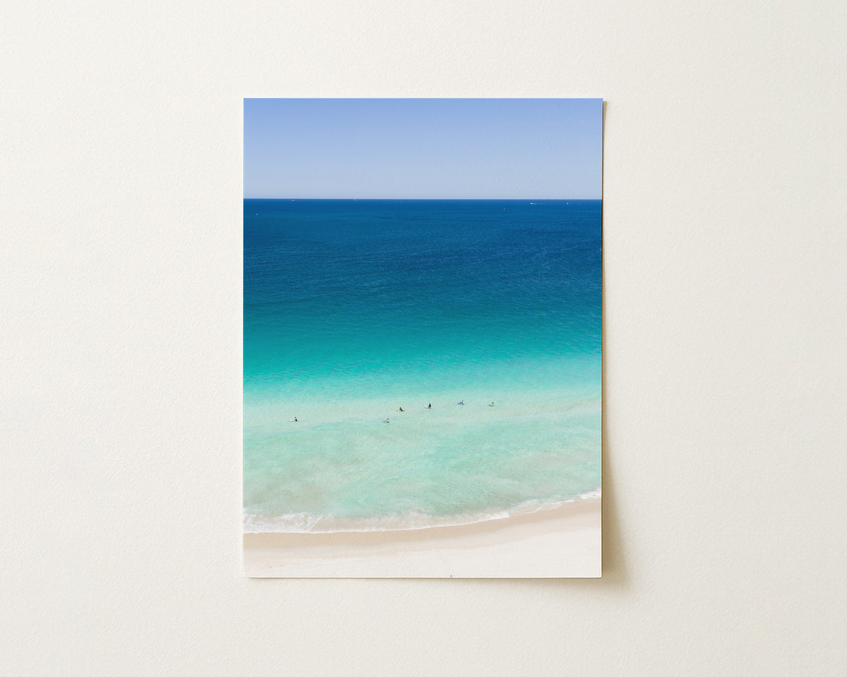 Fine art paper print of aerial photography of Scarborough Beach, deep blue ocean meeting turquoise shallows and a white sand beach with small figures in portrait orientation