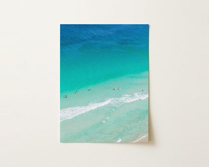 Fine art paper print of aerial photography of Scarborough Beach, surfers and swimmers in deep turquoise water along a diagonal shoreline in portrait orientation