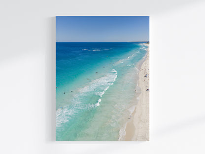 Stretched canvas print of aerial photography of Scarborough Beach, deep blue water, turquoise shallows and pale sand along a diagonal shore in portrait orientation on a wall