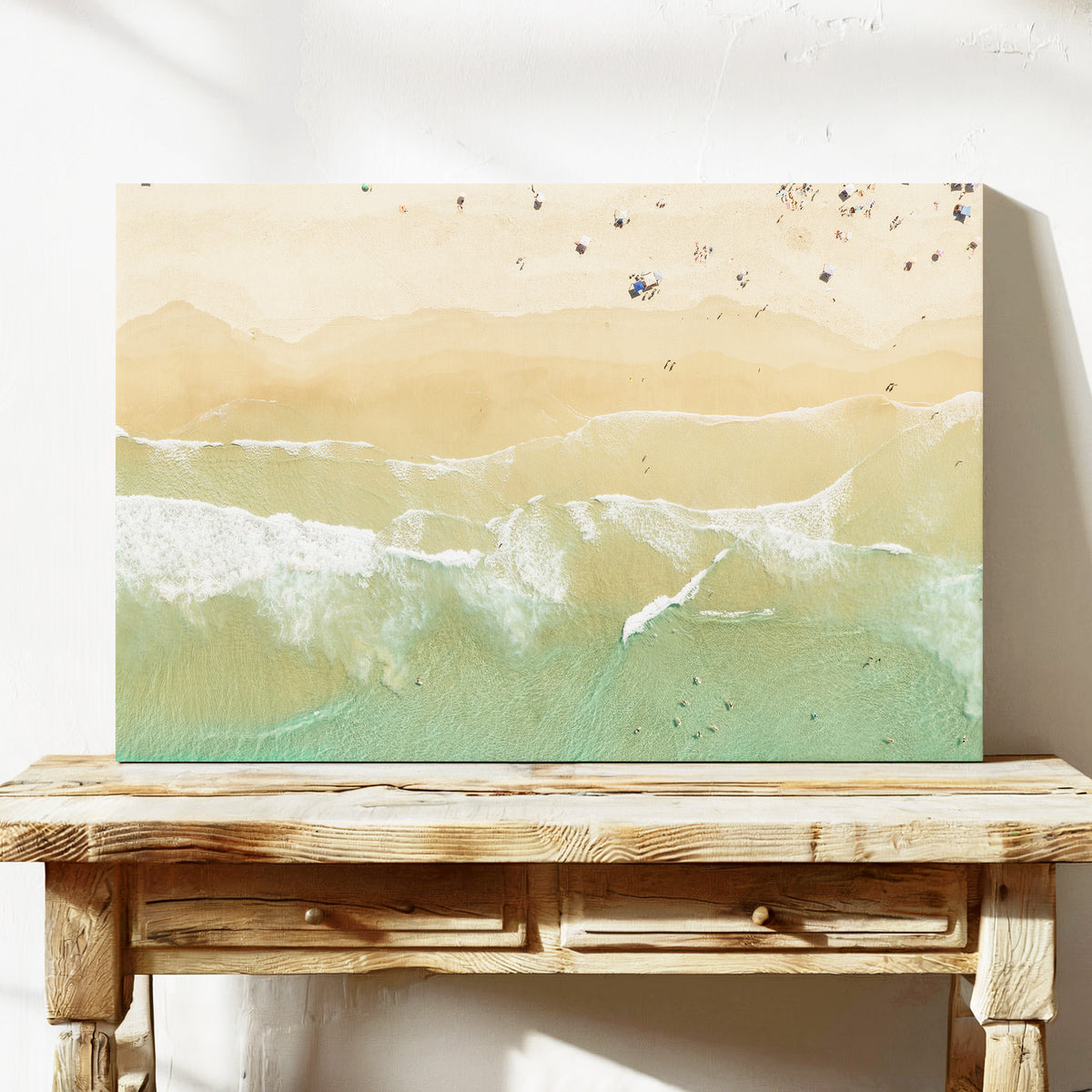 Stretched canvas print of aerial photography of Dreamtime Beach, soft shoreline wash over pale sand with people on the beach on a console table