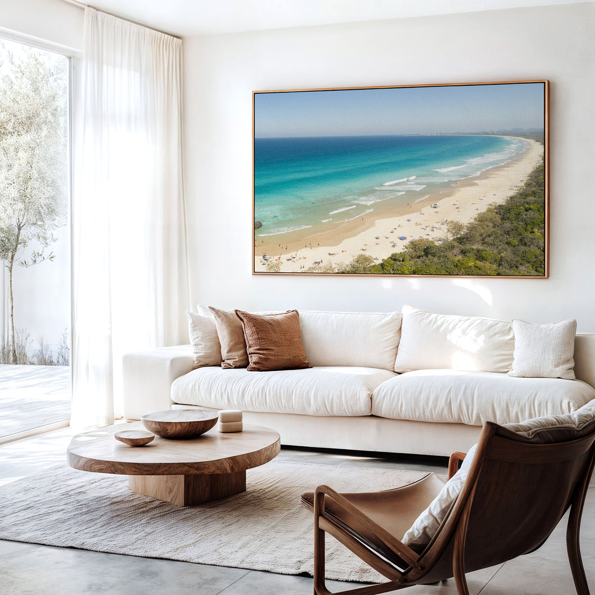 Canvas print of aerial photography of Dreamtime Beach, a long curving beach with turquoise water and coastal bush hanging above a sofa in a living room