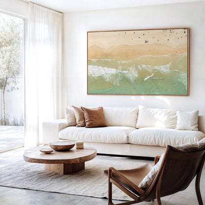 Canvas print of aerial photography of Dreamtime Beach, soft shoreline wash over pale sand with people on the beach hanging above a sofa in a living room