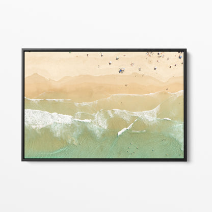 Black framed canvas print of aerial photography of Dreamtime Beach, soft shoreline wash over pale sand with people on the beach