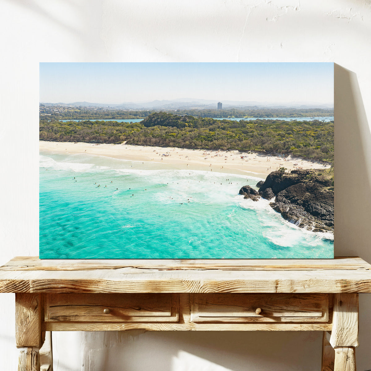 Stretched canvas print of aerial photography of Dreamtime Beach, green coastal bush, a rock outcrop and turquoise water on a console table
