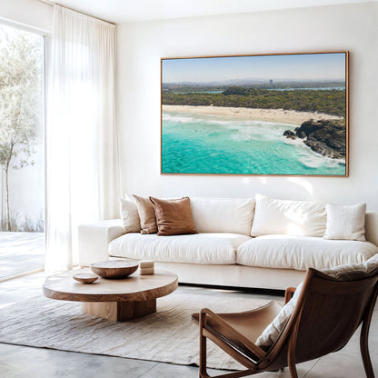 Canvas print of aerial photography of Dreamtime Beach, green coastal bush, a rock outcrop and turquoise water hanging above a sofa in a living room