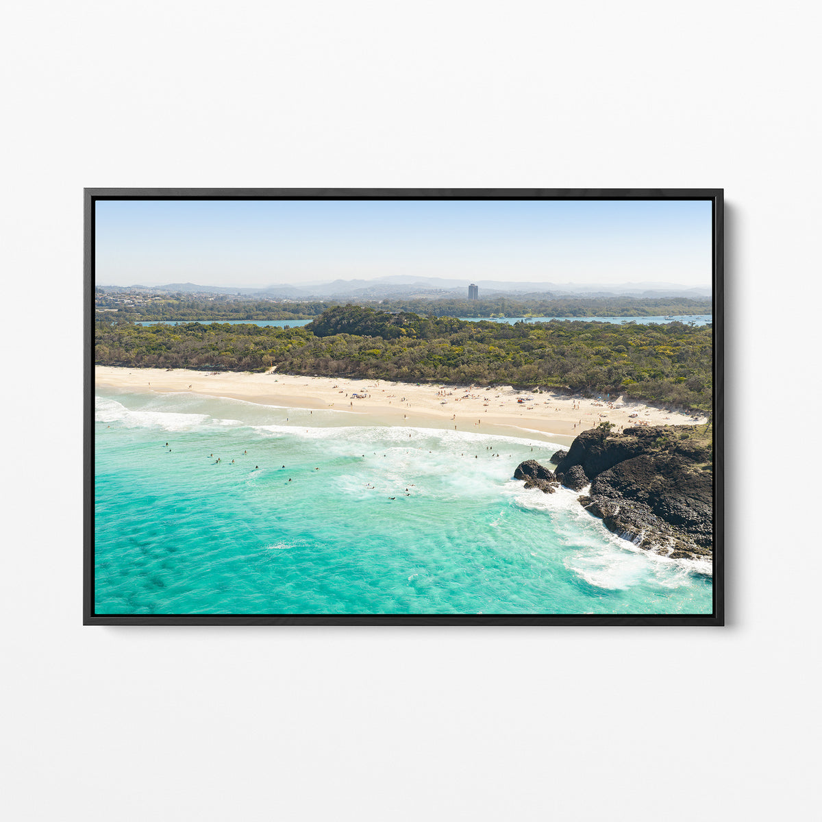 Black framed canvas print of aerial photography of Dreamtime Beach, green coastal bush, a rock outcrop and turquoise water