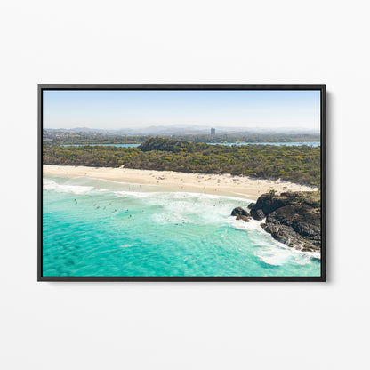 Black framed canvas print of aerial photography of Dreamtime Beach, green coastal bush, a rock outcrop and turquoise water