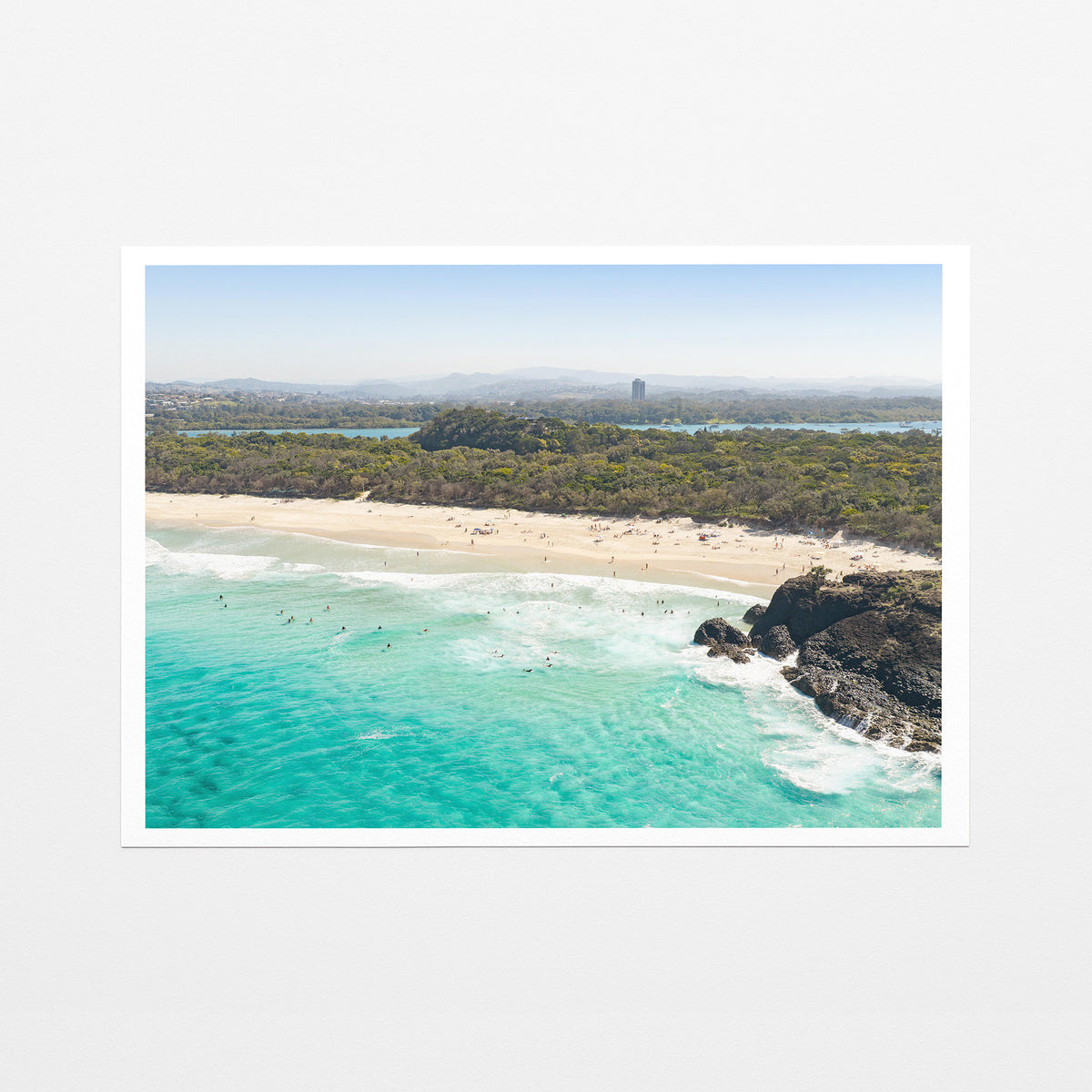 Fine art paper print of aerial photography of Dreamtime Beach, green coastal bush, a rock outcrop and turquoise water with a white border