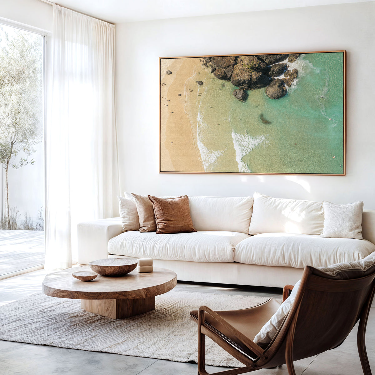Canvas print of aerial photography of Dreamtime Beach, a dark rock outcrop beside golden sand and green water hanging above a sofa in a living room