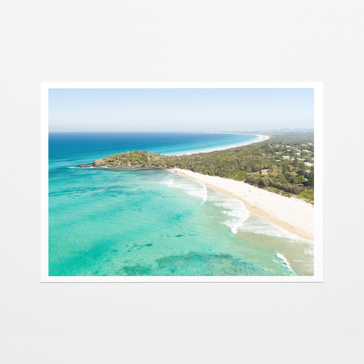 Fine art paper print of aerial photography of Fingal Head, a bush covered headland with houses, a sandy beach and turquoise reef water with a white border