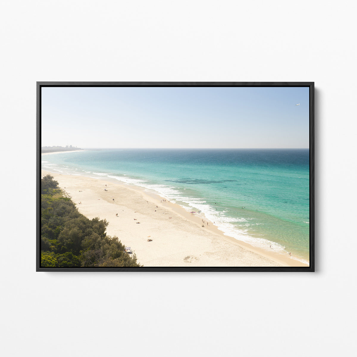 Black framed canvas print of aerial photography of Fingal Head, a pale sand beach with coastal bush in the bottom left and turquoise water