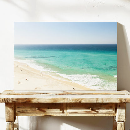 Stretched canvas print of aerial photography of Fingal Head, a long strip of sand with turquoise surf rolling onto the shore on a console table