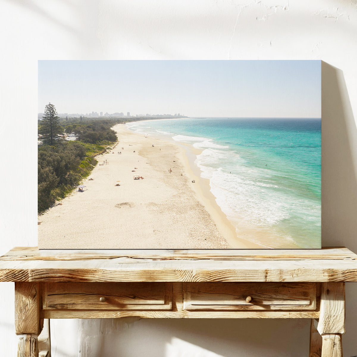 Stretched canvas print of aerial photography of Fingal Head, a long sandy beach with bush on the left and surf rolling onto the shore on a console table