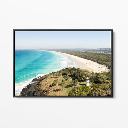 Black framed canvas print of aerial photography of Fingal Head Lighthouse, a white lighthouse on a bush headland above a long beach and turquoise sea