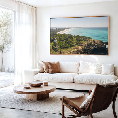 Canvas print of aerial photography of Fingal Head Lighthouse, bushland with a dirt track, a rocky cliff, the beach and turquoise sea hanging above a sofa in a living room