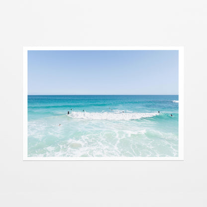 Fine art paper print of aerial photography of Scarborough Beach, a wide view of surfers spread across turquoise water and white foam with a white border