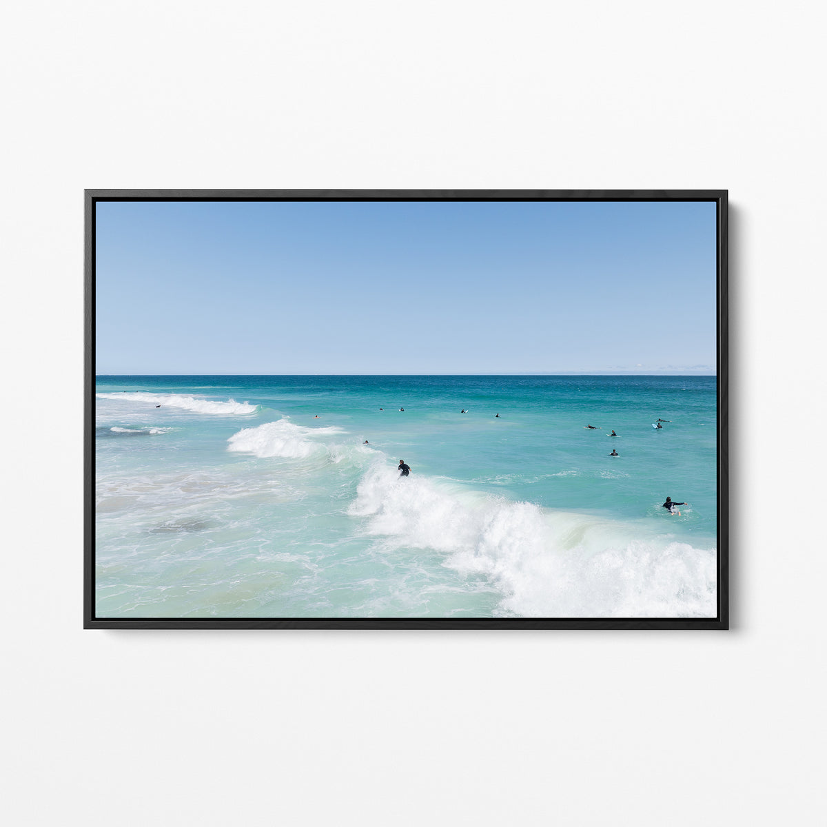 Black framed canvas print of aerial photography of Scarborough Beach, a surfer riding a breaking wave with white foam in turquoise water