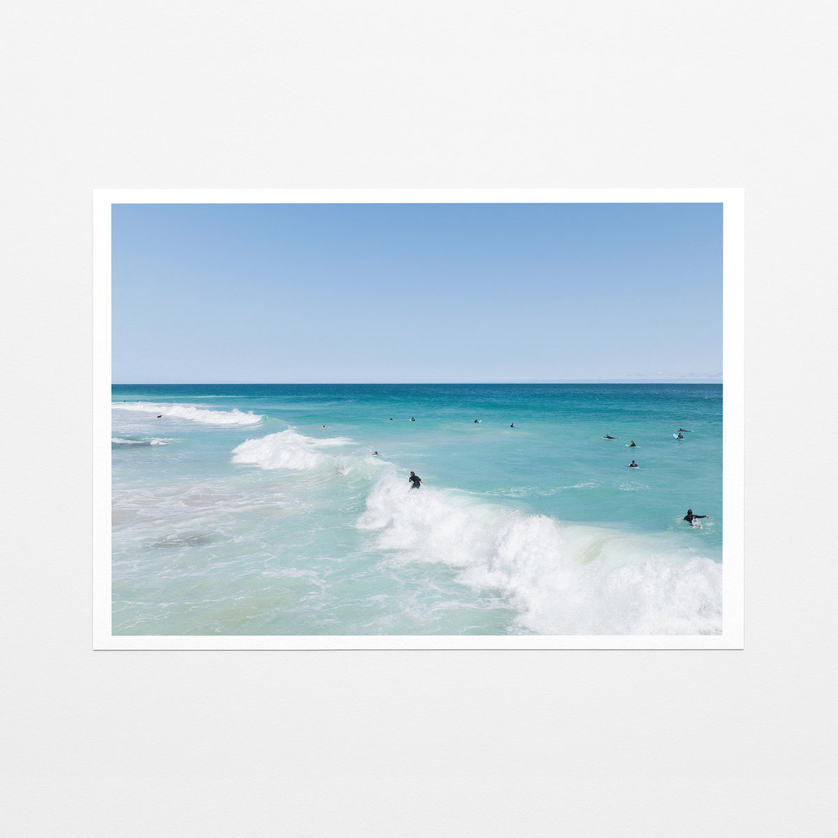 Fine art paper print of aerial photography of Scarborough Beach, a surfer riding a breaking wave with white foam in turquoise water with a white border