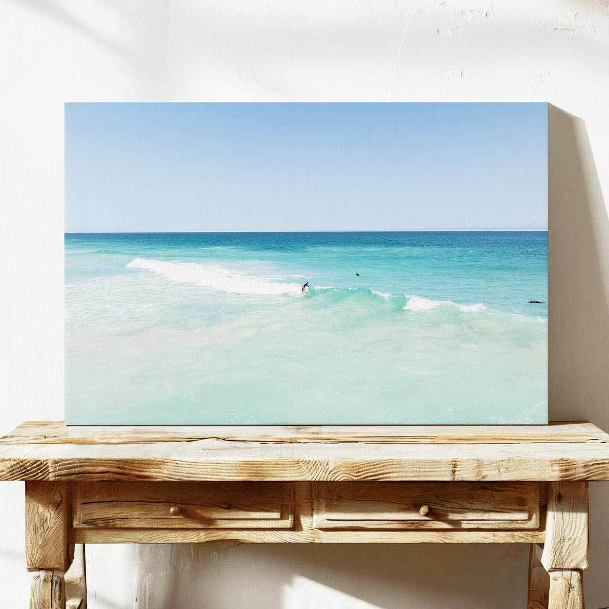 Stretched canvas print of aerial photography of Scarborough Beach, a surfer on a breaking wave in pale turquoise water on a console table