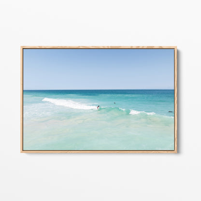 Oak framed canvas print of aerial photography of Scarborough Beach, a surfer on a breaking wave in pale turquoise water