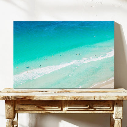 Stretched canvas print of aerial photography of Scarborough Beach, surfers and swimmers in deep turquoise water along a diagonal shoreline on a console table