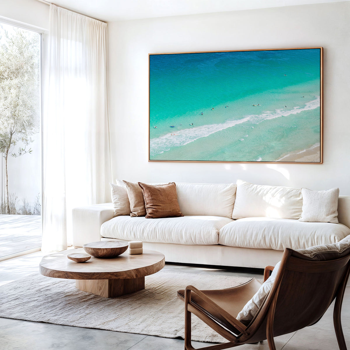 Canvas print of aerial photography of Scarborough Beach, surfers and swimmers in deep turquoise water along a diagonal shoreline hanging above a sofa in a living room