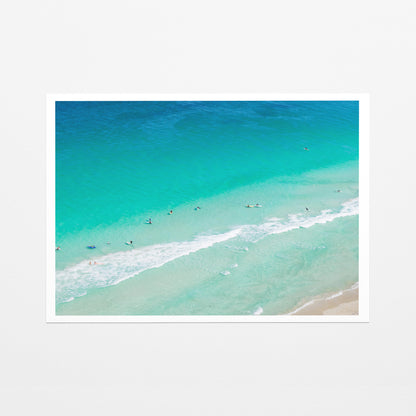 Fine art paper print of aerial photography of Scarborough Beach, surfers and swimmers in deep turquoise water along a diagonal shoreline with a white border