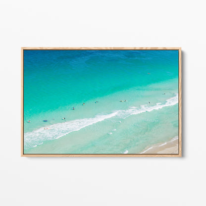 Oak framed canvas print of aerial photography of Scarborough Beach, surfers and swimmers in deep turquoise water along a diagonal shoreline