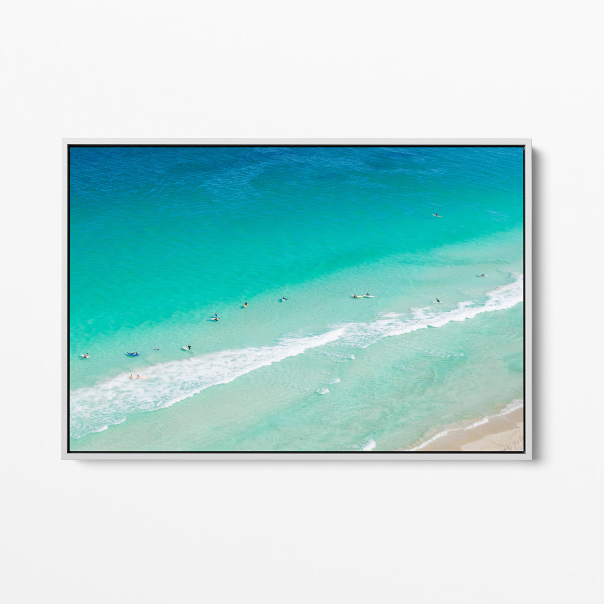 White framed canvas print of aerial photography of Scarborough Beach, surfers and swimmers in deep turquoise water along a diagonal shoreline