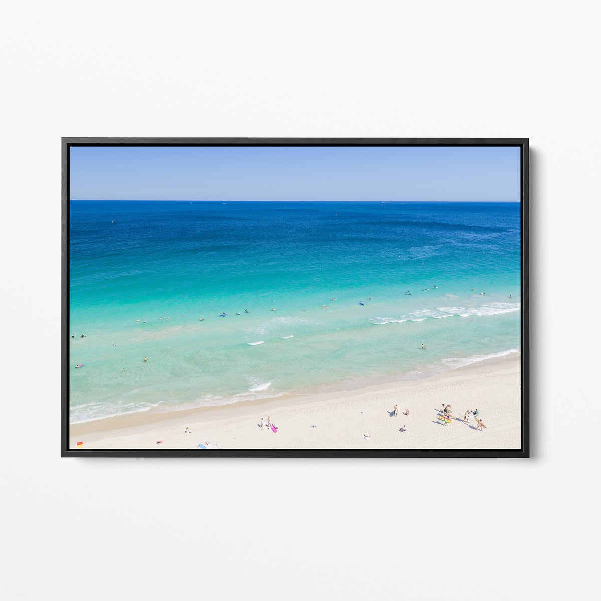 Black framed canvas print of aerial photography of Scarborough Beach, deep blue ocean meeting turquoise shallows and a white sand beach with small figures