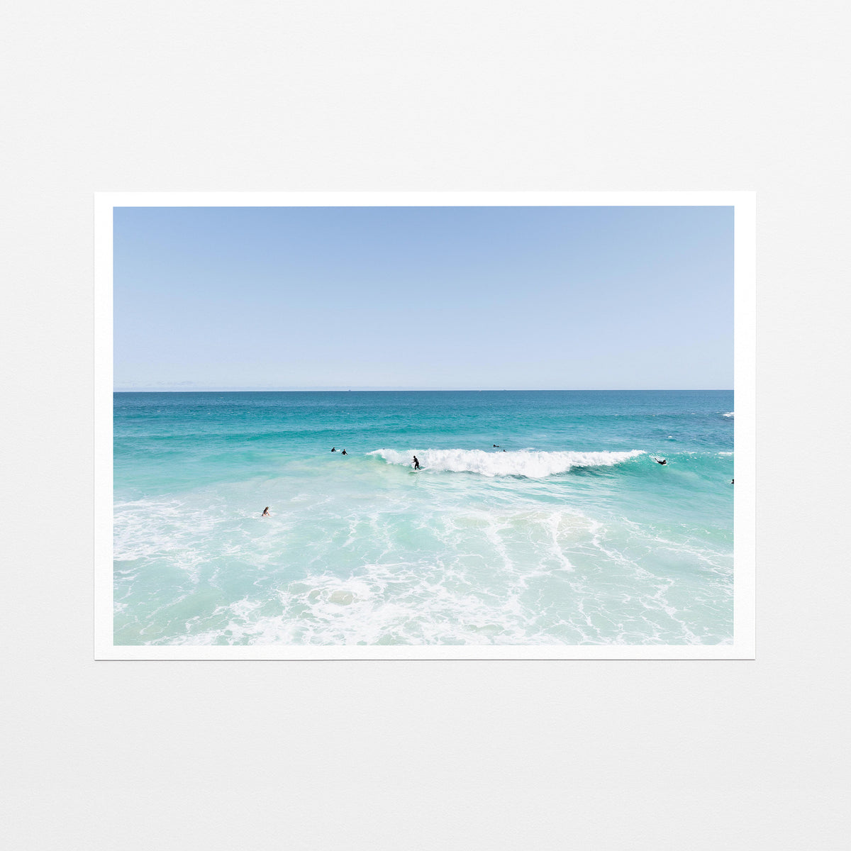 Fine art paper print of aerial photography of Scarborough Beach, surfers waiting beside a small breaking wave in turquoise water with a white border