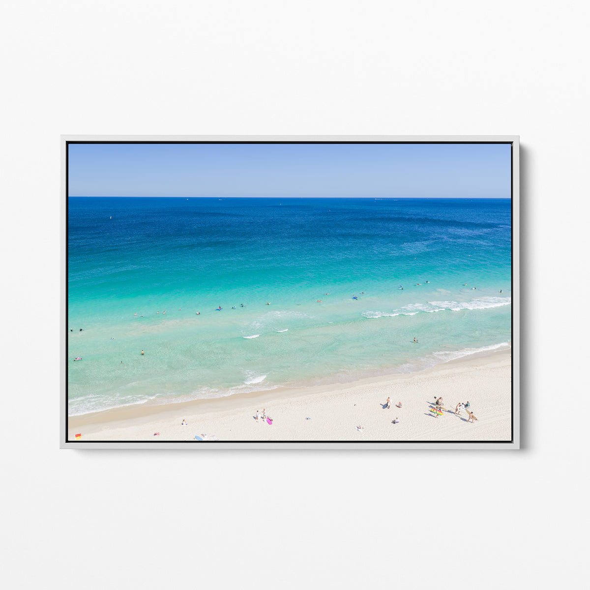 White framed canvas print of aerial photography of Scarborough Beach, deep blue ocean meeting turquoise shallows and a white sand beach with small figures