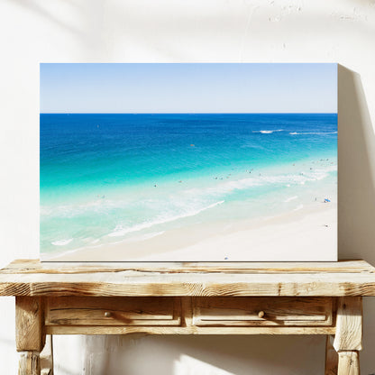 Stretched canvas print of aerial photography of Scarborough Beach, deep blue water, turquoise shallows and pale sand along a diagonal shore on a console table