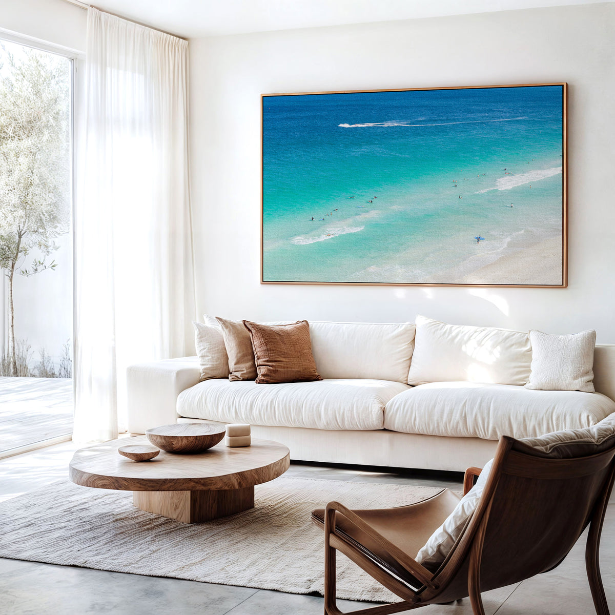 Canvas print of aerial photography of Scarborough Beach, surfers in blue and turquoise water along a diagonal shoreline with white foam lines hanging above a sofa in a living room
