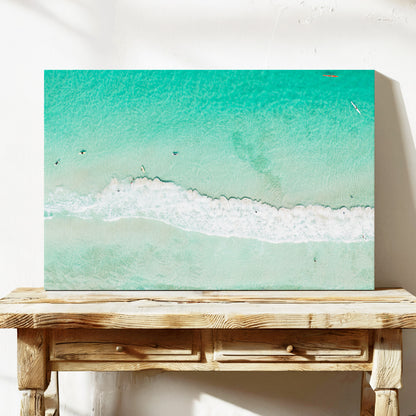 Stretched canvas print of aerial photography of Scarborough Beach, a line of white wave across green turquoise shallows with shadows on the sea floor on a console table