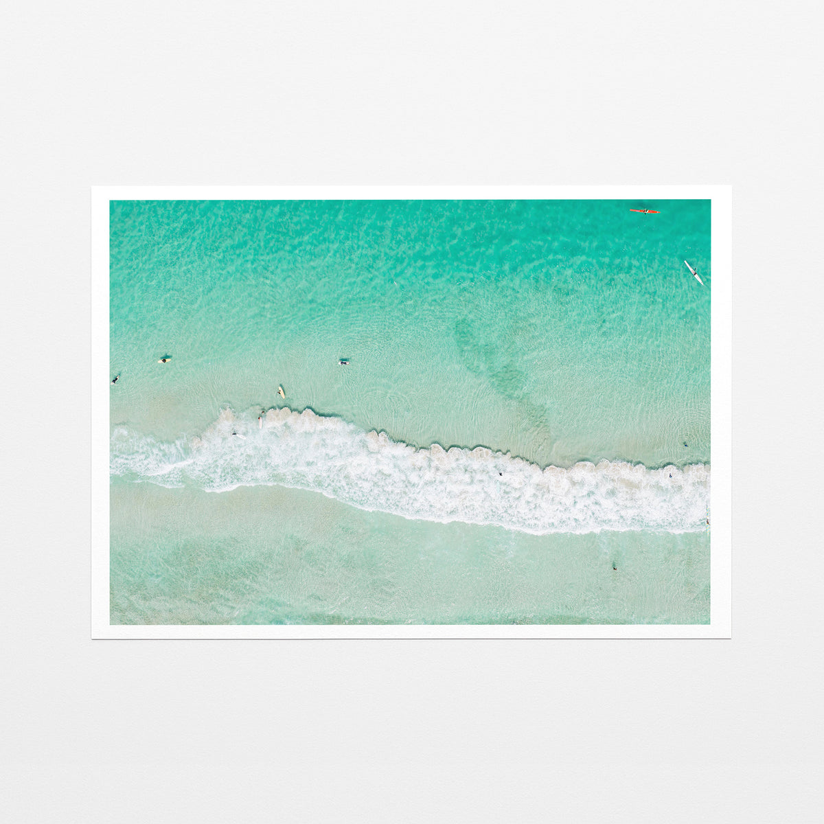 Fine art paper print of aerial photography of Scarborough Beach, a line of white wave across green turquoise shallows with shadows on the sea floor with a white border