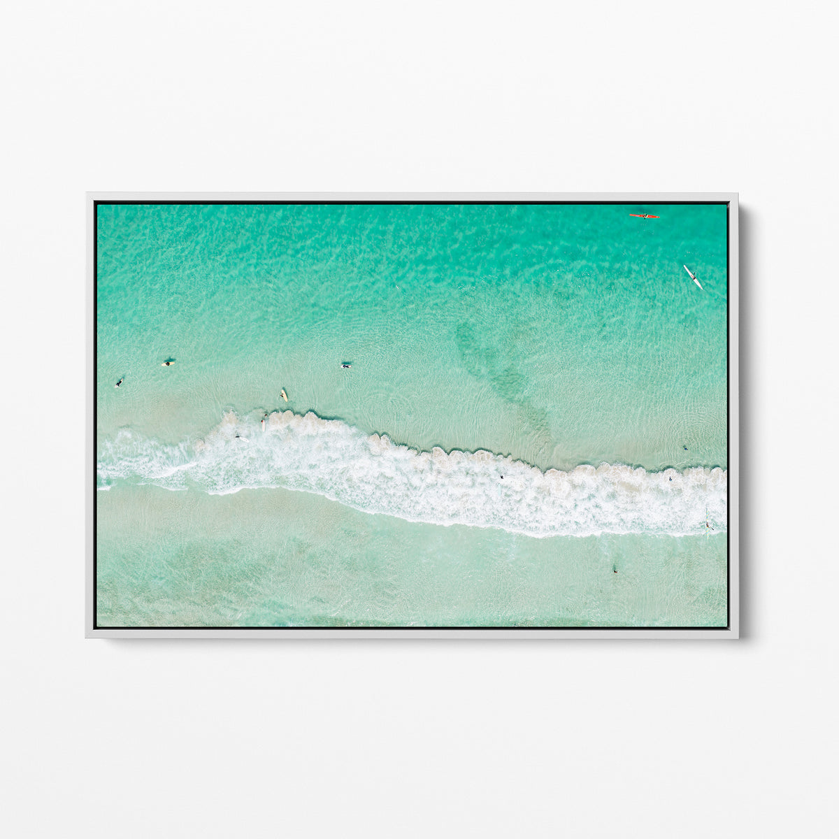 White framed canvas print of aerial photography of Scarborough Beach, a line of white wave across green turquoise shallows with shadows on the sea floor