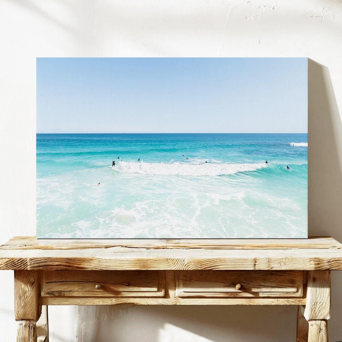 Stretched canvas print of aerial photography of Scarborough Beach, a wide view of surfers spread across turquoise water and white foam on a console table
