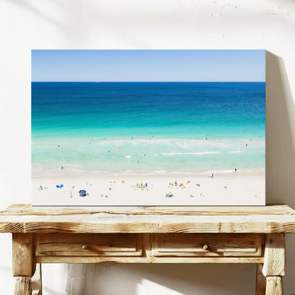 Stretched canvas print of aerial photography of Scarborough Beach, colourful umbrellas and people on white sand beside turquoise water and deep blue ocean on a console table