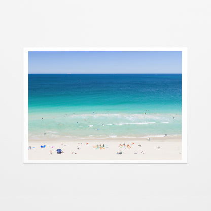 Fine art paper print of aerial photography of Scarborough Beach, colourful umbrellas and people on white sand beside turquoise water and deep blue ocean with a white border